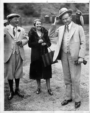 Former President Coolidge with a parrot as his wife and Mr. William Wrigley look on and laugh.