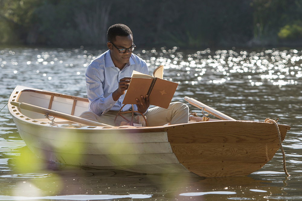 A man in a boat reading a book.