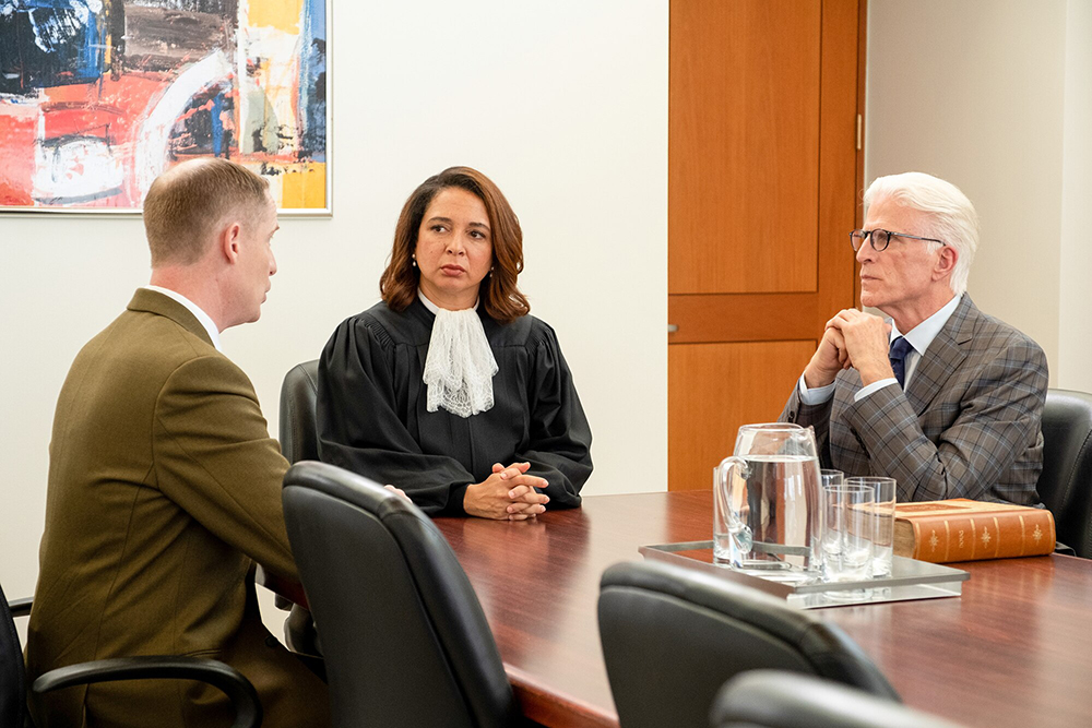 A judge sits at a table with two other people.